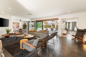 Una sala de estar moderna con un sofá, sillones, una mesa de centro y un televisor montado en la pared.