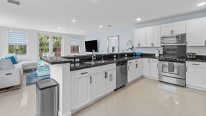 A modern kitchen with white cabinets, stainless steel appliances, and a large island with a sink. - BY THE SEA VACATION VILLAS 4 BED/PRIVATE POOL/STEPS TO THE BEACH (Lauderdale-by-the-Sea)