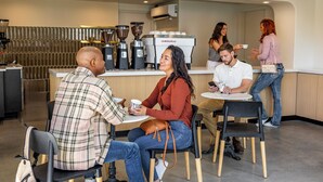 Un interior de cafetería con mesas, sillas y una máquina de café.