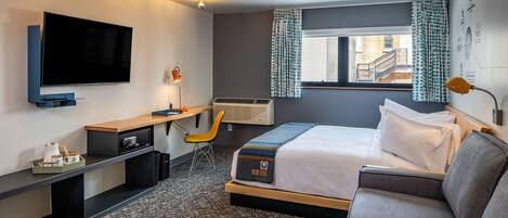 A modern hotel room with a large bed, a desk with a chair, a flat-screen TV, and a window with curtains.