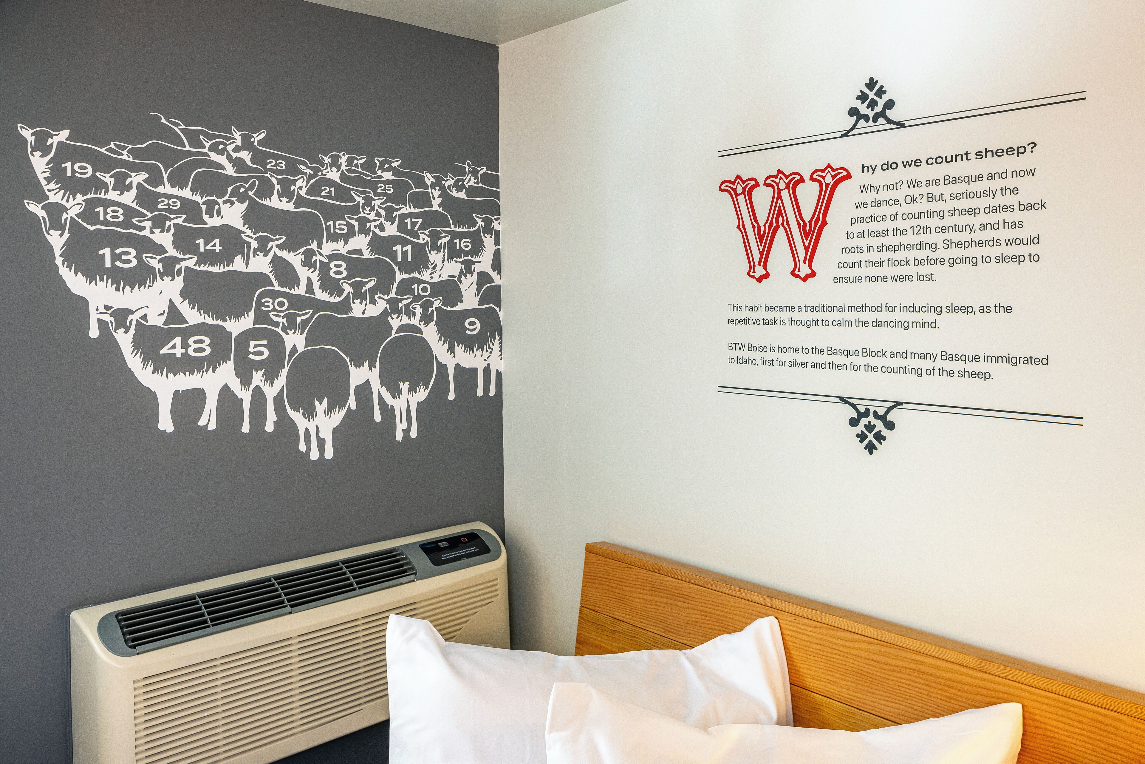 Habitación de hotel con un mural que muestra una oveja contando, junto a un texto que explica su origen.