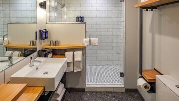 Une salle de bain moderne équipée d’un lavabo, d’un miroir, d’un porte-serviettes, d’une douche et de toilettes.