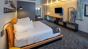 Ein modernes Hotelzimmer mit einem großen Bett, einem Schreibtisch, einem Fernseher und einem Bademantel, der an der Wand hängt.