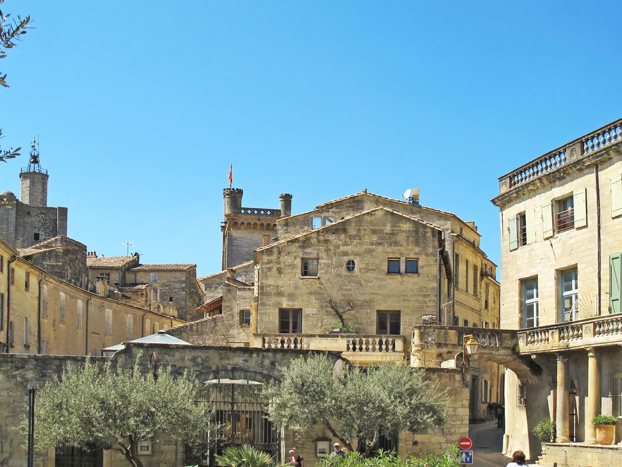 A historic stone building with a central courtyard, featuring a bell tower and a flag.