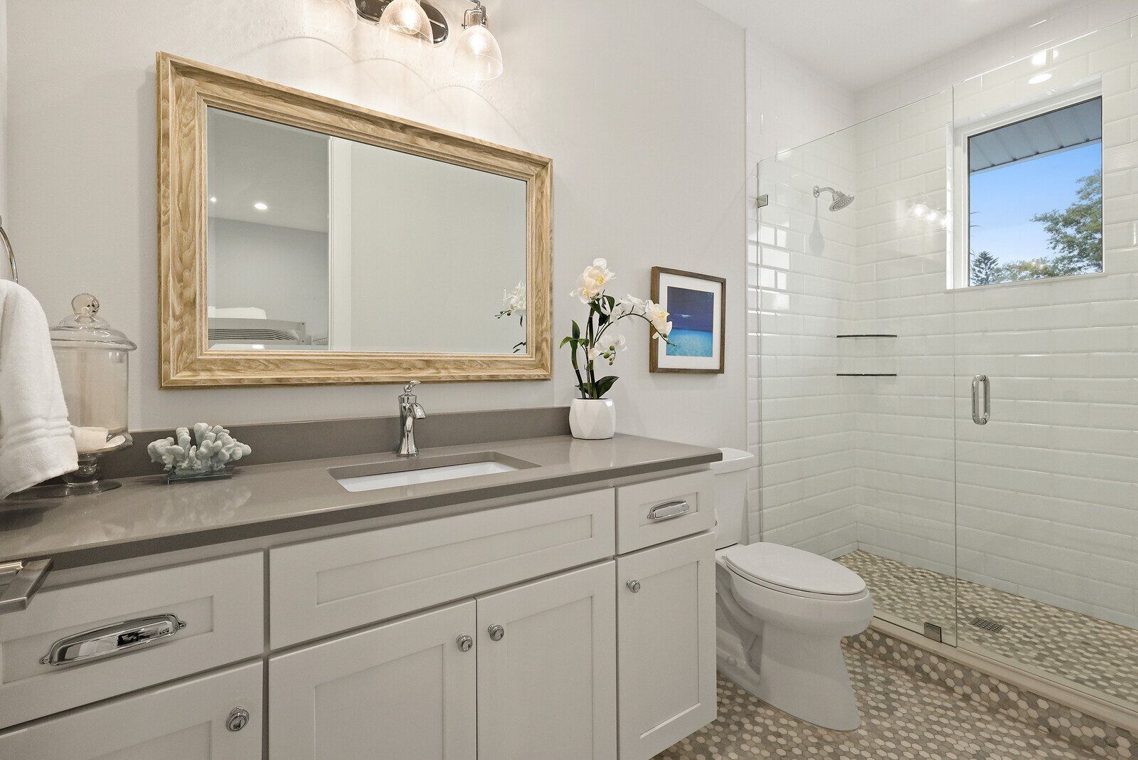 A modern bathroom with a large mirror, a sink, a toilet, and a shower area.