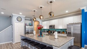 A modern kitchen with a central island, stainless steel appliances, and a blue accent wall. - Amazing Bowling Alley Home, Orlando Mansion 6223 (Orlando)