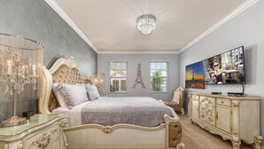A spacious bedroom with a large bed, a chandelier, a dresser, and a painting of the Eiffel Tower. - Amazing Bowling Alley Home, Orlando Mansion 6223 (Orlando)