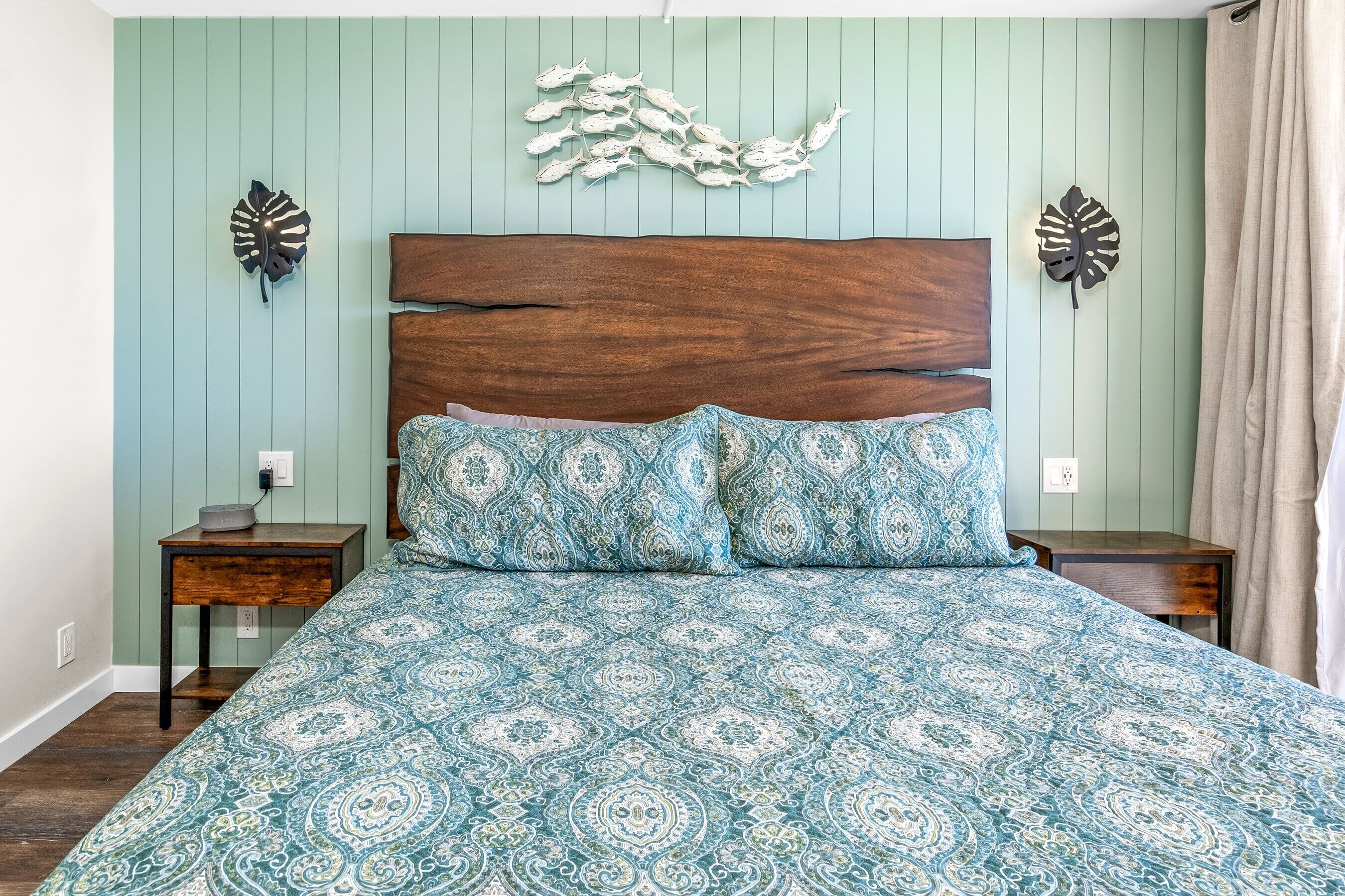 Een slaapkamer met een houten hoofdbord, een bed met een decoratief sprei en wanddecoratie.