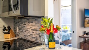 A kitchen with a microwave, a knife block, a bottle of Veuve Clicquot champagne, and two glasses on a marble countertop. - 2 2 Oceanview Modern Resort Vistas (Kihei)