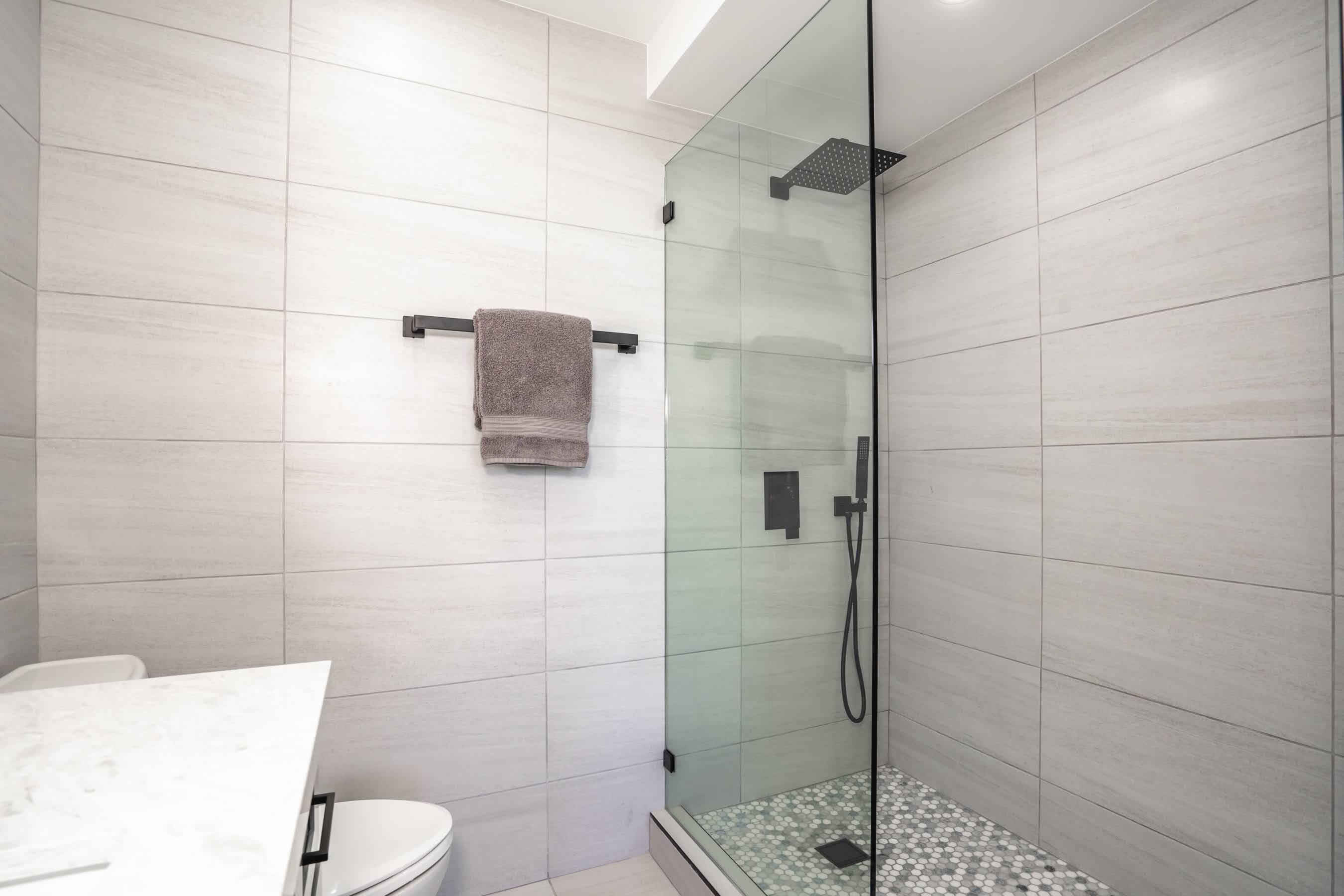 Een moderne badkamer met een douchecabine, toilet en handdoekhouder.