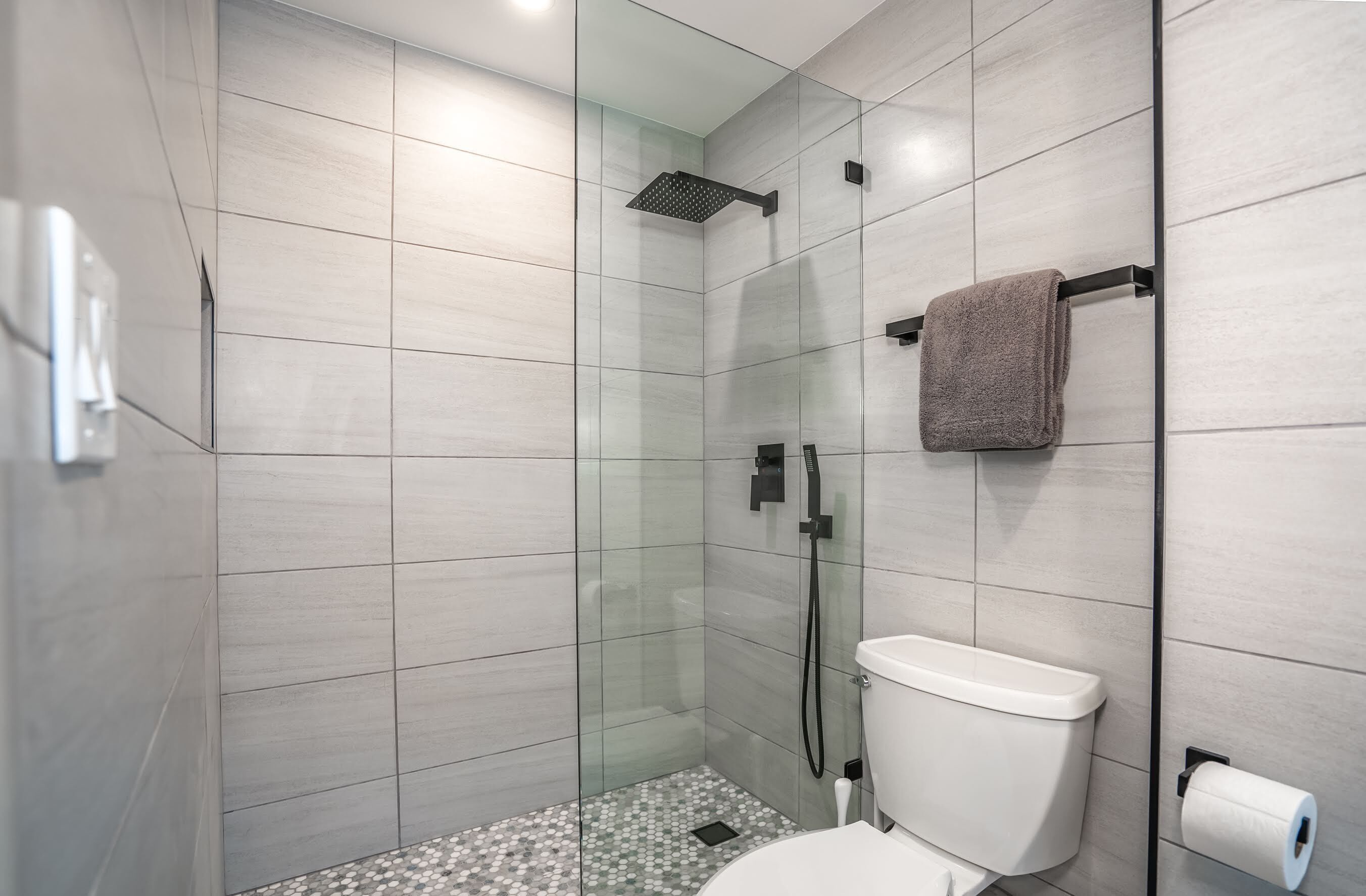 A modern bathroom with a glass-enclosed shower, a toilet, and a towel rack.