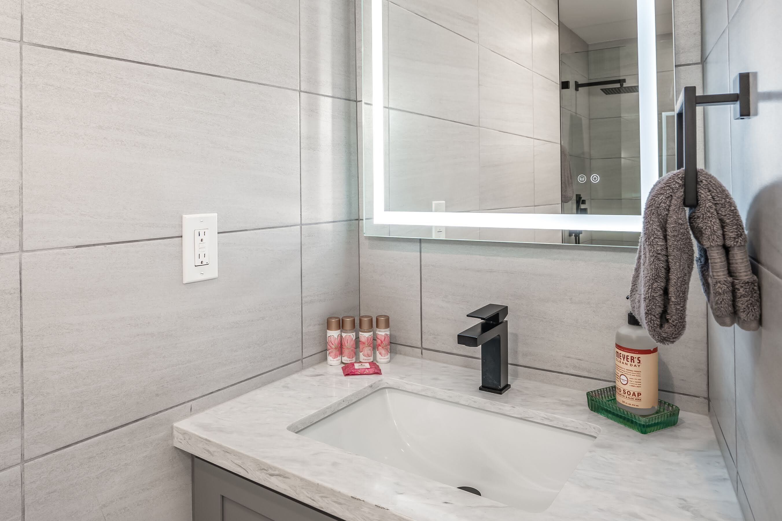 A modern bathroom with a large mirror, a sink, and a towel rack.