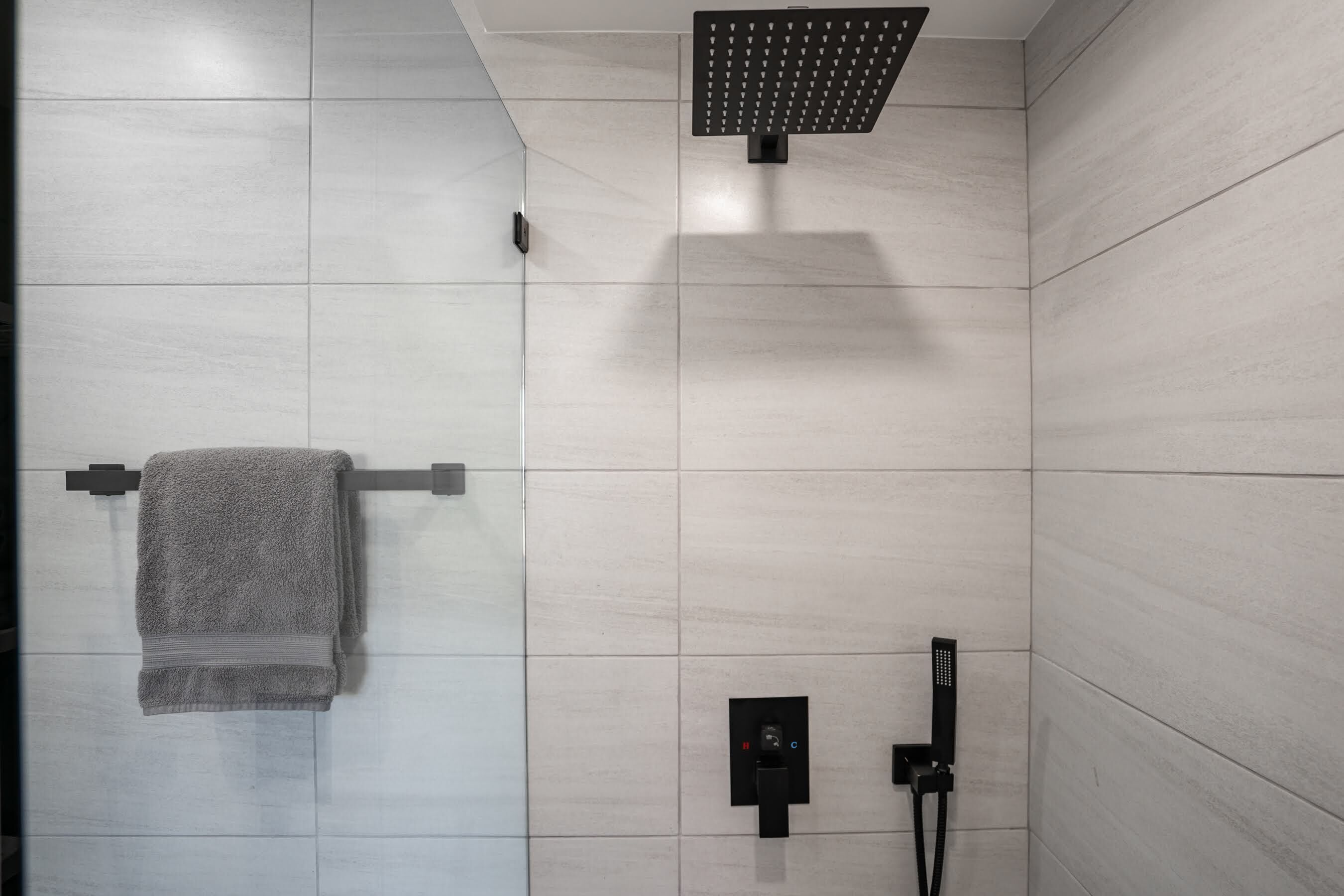 Un baño moderno con ducha, toallero y panel de control.