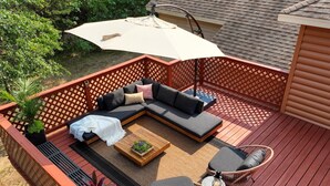 A deck with a sofa, two chairs, a small table, and a canopy. - Modern, secluded luxury cabin near Castle Rock & Petenwell Lakes + Wisc. Dells (Necedah)