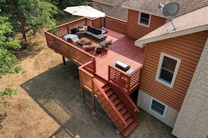 A deck with a sofa, a table, and a chair. There is a satellite dish on the roof.
