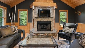 A cozy living room with a stone fireplace, wooden ceiling, and a comfortable seating area. - Modern, secluded luxury cabin near Castle Rock & Petenwell Lakes + Wisc. Dells (Necedah)