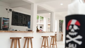 Una zona de bar con taburetes de madera, un menú en una pizarra y un letrero negro con una calavera y tibias cruzadas.