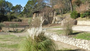 A rustic stone building with a tiled roof, surrounded by a stone wall and vegetation. - Saint-Michel by Interhome (Draguignan)