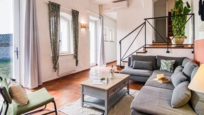 A living room with a sofa, a coffee table, a chair, and a staircase with a plant. - Saint-Michel by Interhome (Draguignan)