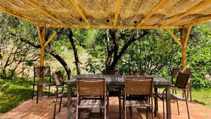 An outdoor dining area with a pergola overhead, surrounded by trees and greenery. - Saint-Michel by Interhome (Draguignan)