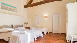 A hotel room with two beds, a small table, a nightstand, and a wall-mounted lamp. - Saint-Michel by Interhome (Draguignan)