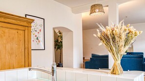A modern bathroom with a double sink, a wooden cabinet, a framed botanical illustration, and a vase of dried flowers. - Les Grenaches by Interhome (Draguignan)