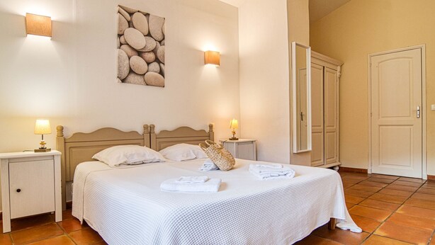 A neatly arranged bedroom with a bed, two bedside tables, a wall-mounted artwork, and a door. - Les Grenaches by Interhome (Draguignan)