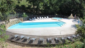 A swimming pool with multiple lanes, surrounded by lounge chairs and a wooden deck. - Les Grenaches by Interhome (Draguignan)