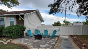 A patio area with stone flooring, a white fence, and blue chairs.