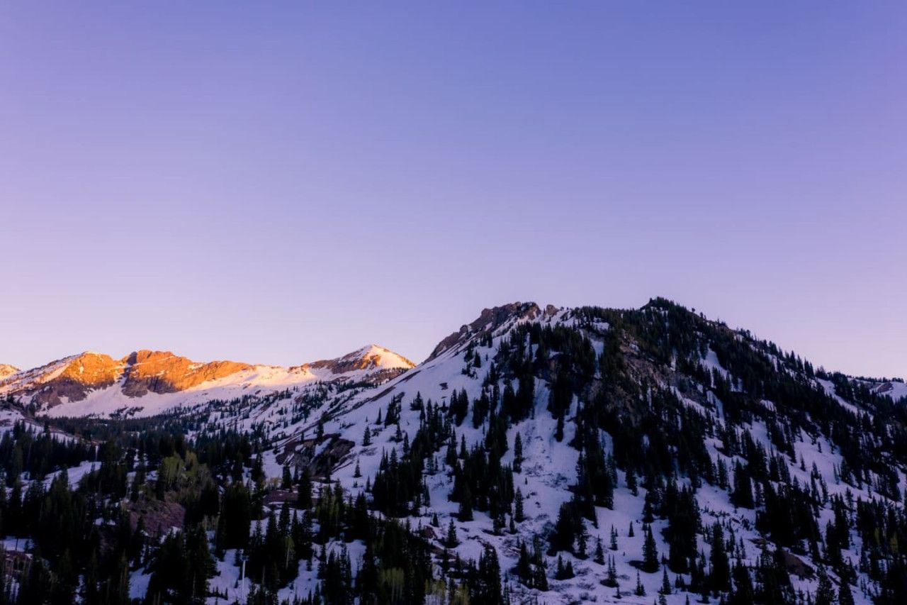 A mountain landscape with snow-covered slopes and dense forests.