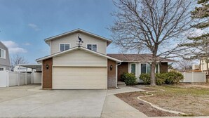 A single-story house with a garage, a small front yard with a tree, and a clear sky.