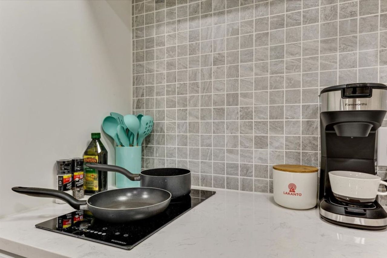 Eine Küche mit einem Herd, Töpfen, einer Kaffeemaschine und einer Tasse.