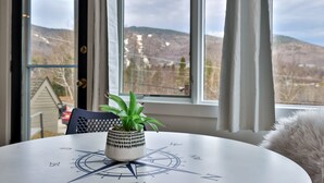 A round table with a compass design, a potted plant, and a view of mountains through large windows.