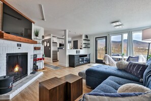 Uma sala de estar moderna com lareira, um sofá e vista para as montanhas.