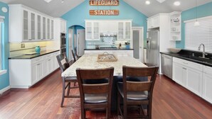 A kitchen with white cabinets, a granite countertop, and a dining area with wooden chairs.