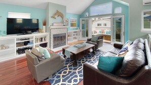A living room with a fireplace, a television, and a view of the outside.