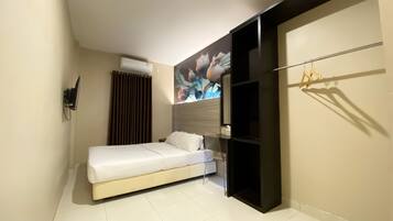 Une chambre moderne équipée d’un lit, d’une armoire et d’un climatiseur fixé au mur.