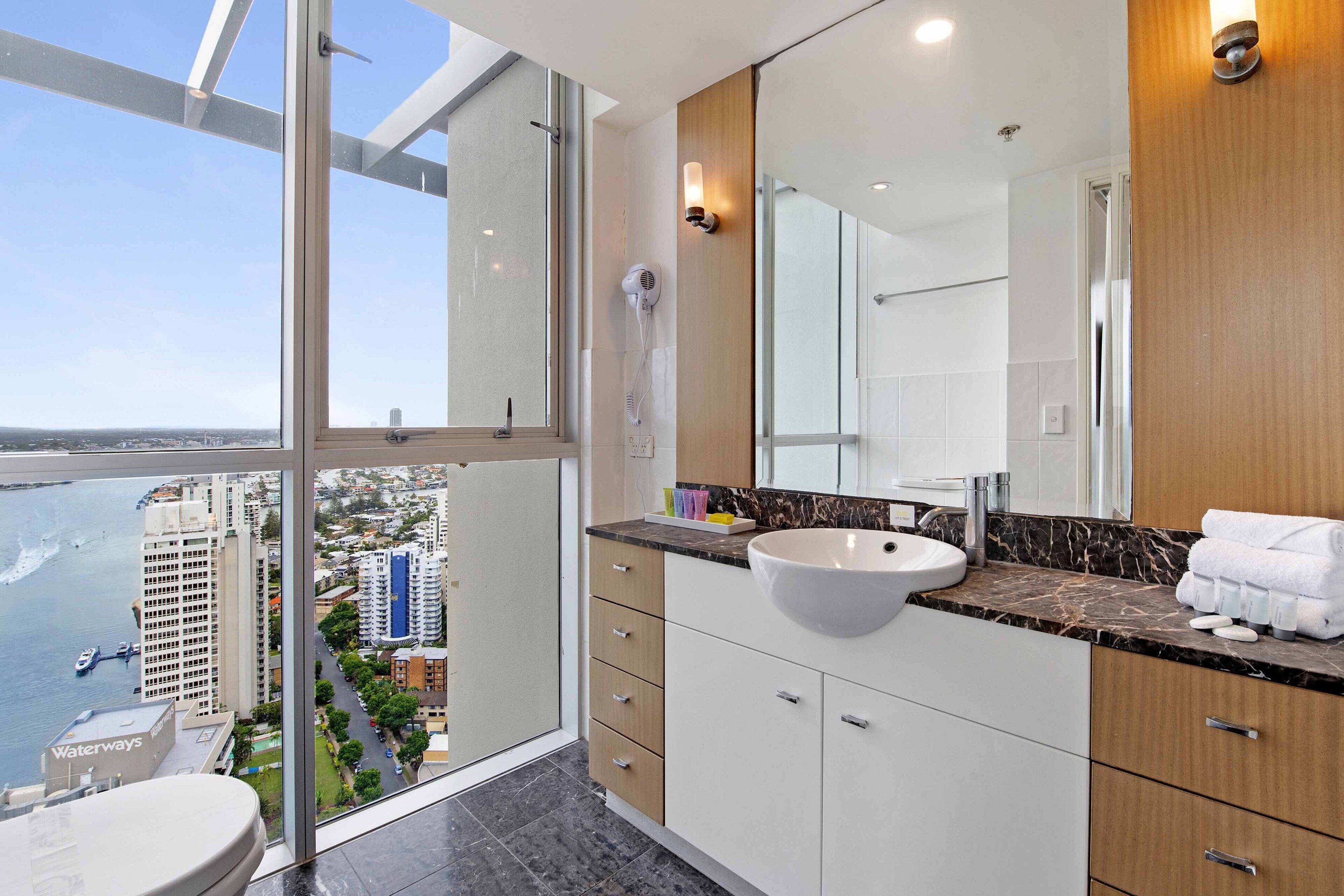 A modern bathroom with a large window, a sink, and a mirror.