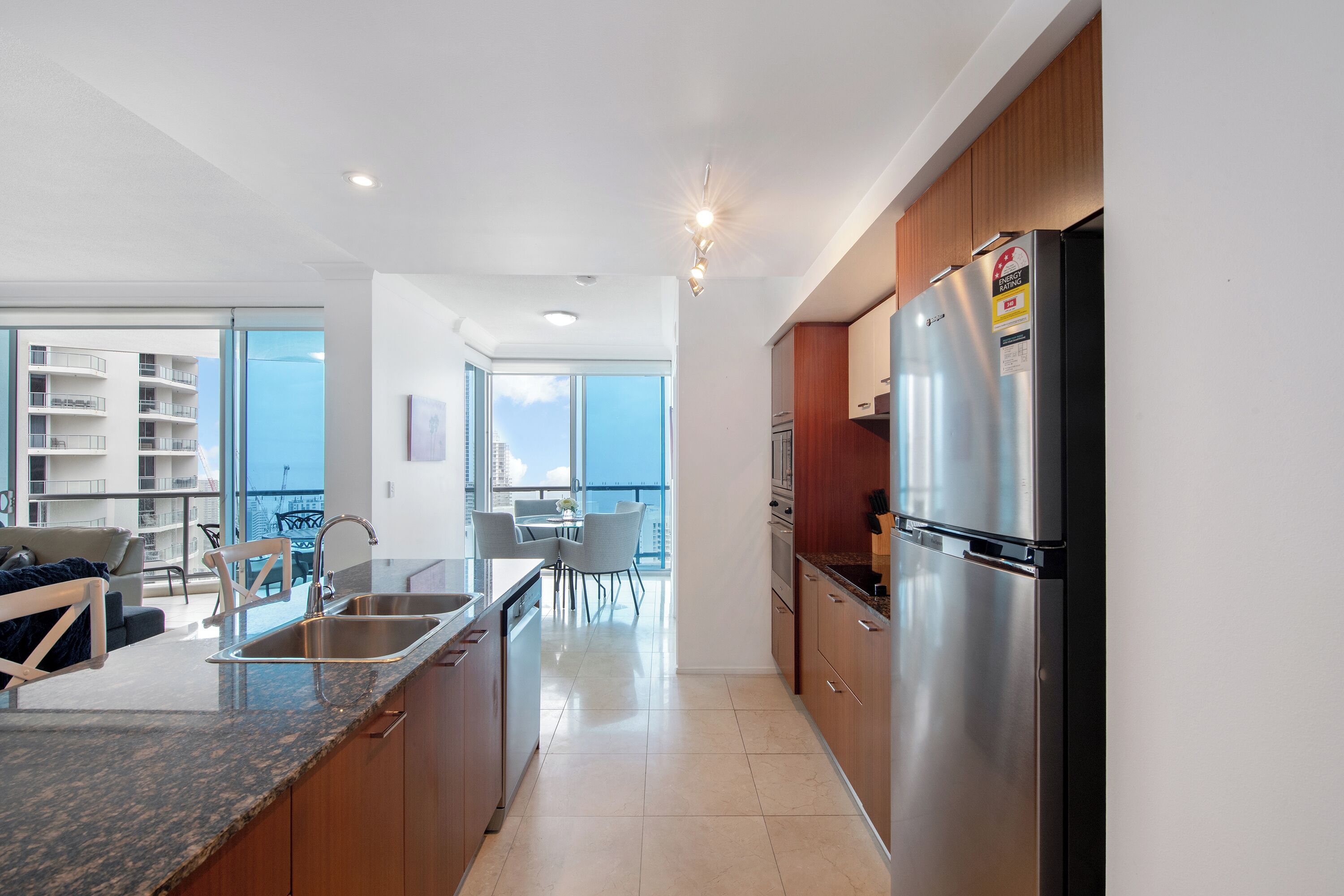A modern kitchen with stainless steel appliances, a dining area with a view, and a balcony with a cityscape.