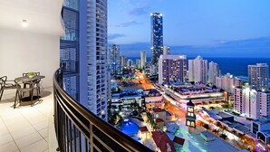 A high-rise hotel with a balcony featuring a dining area, a pool, and a view of the cityscape and ocean. - Chevron Renaissance - WOWSTAY (Surfers Paradise)