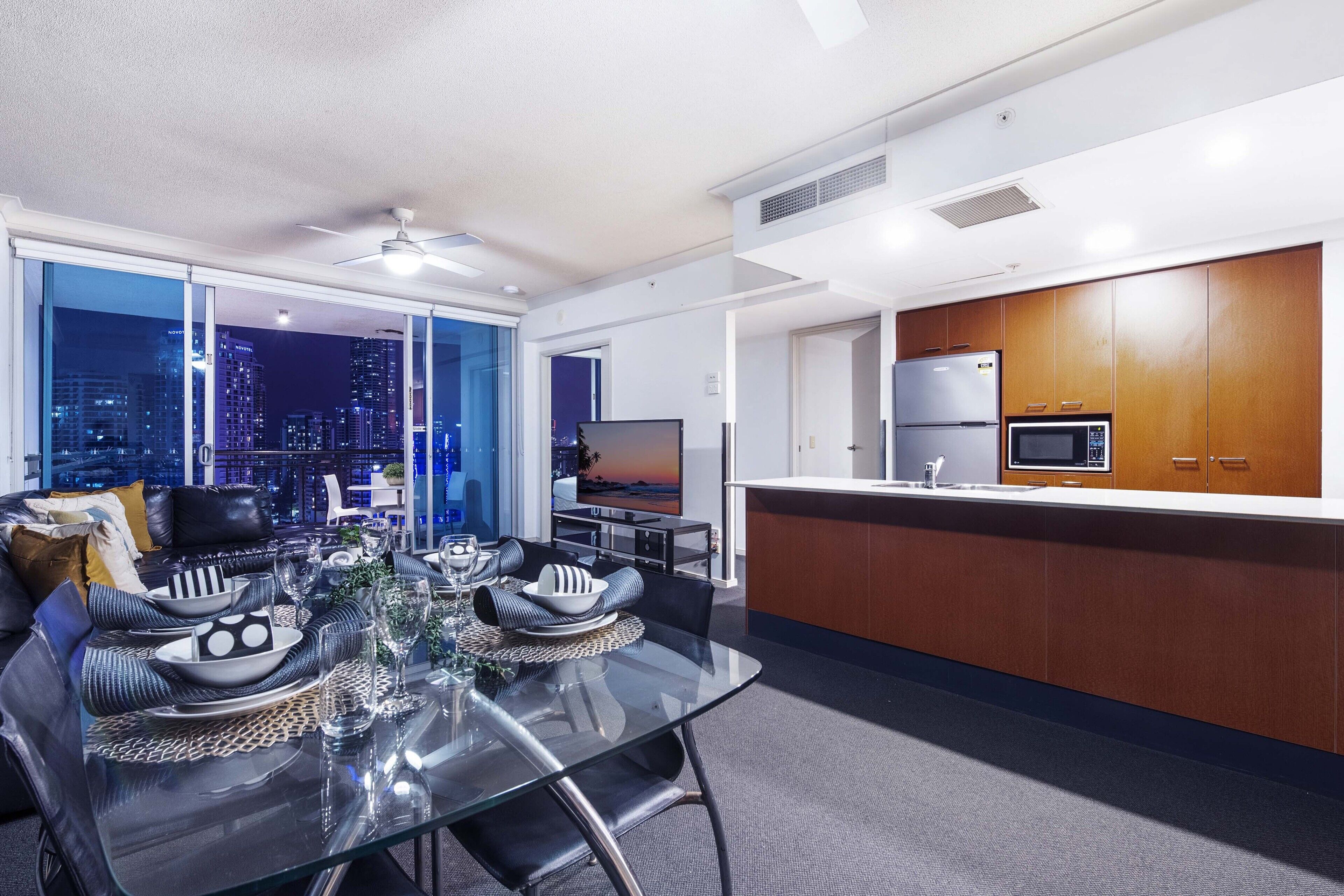 A modern kitchen with a microwave, refrigerator, and dining area with a glass table and chairs.