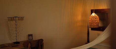 A room with a bed, a desk, a chair, a hanging light fixture, and a 'No Smoking' sign.