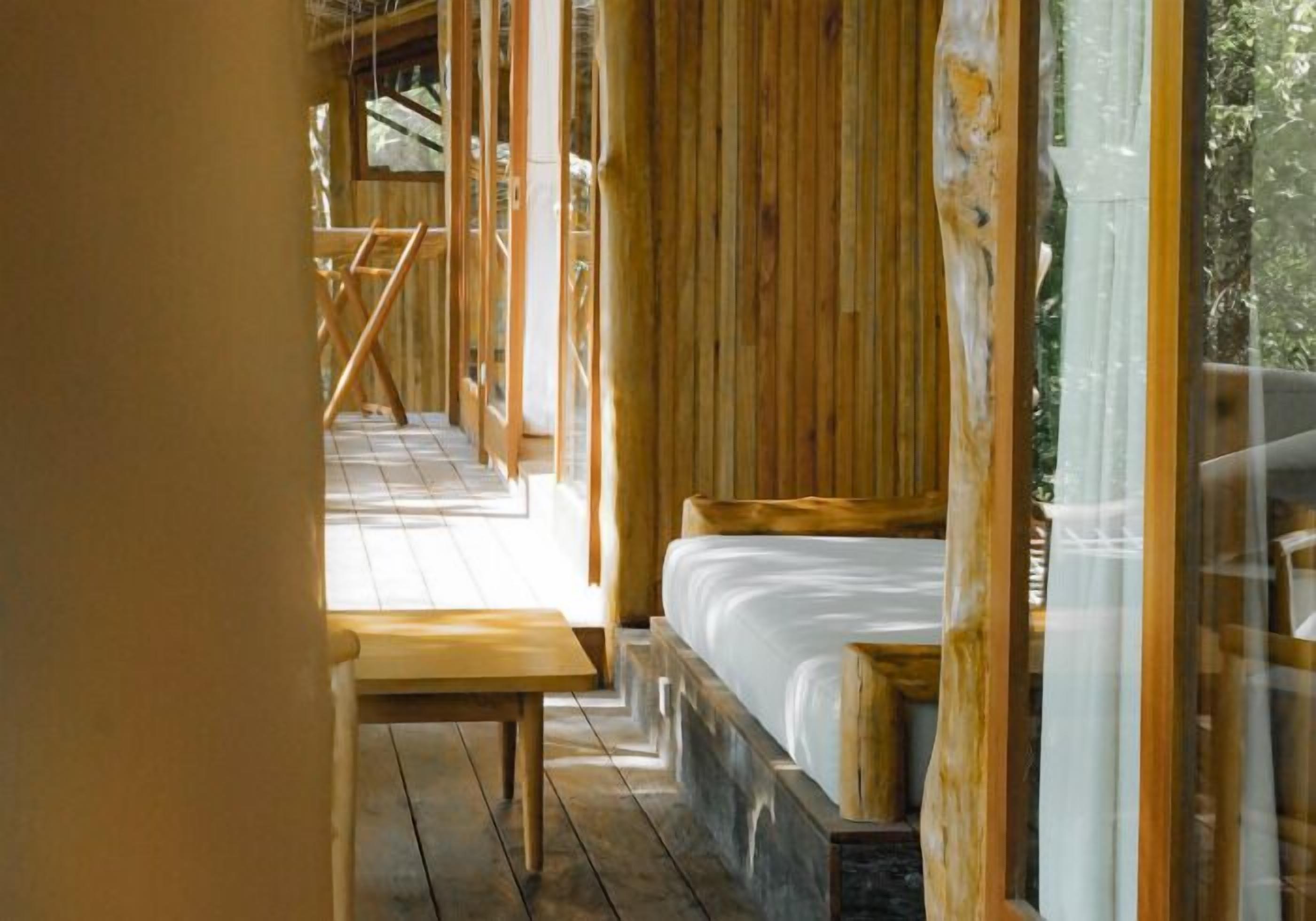 Ein Holzblockhaus-Interieur mit einem Bett, einer Bank und einer Treppe zu einer oberen Ebene.