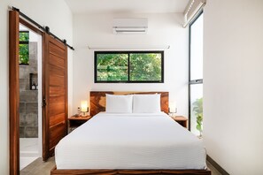 Una camera da letto con un letto grande, una testiera in legno, due comodini con lampade, una finestra vista alberi e una porta scorrevole.