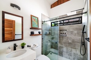 Un bagno moderno con uno specchio grande, un lavandino bianco, un box doccia in vetro e un armadietto in legno.