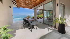 A terrace with a wooden pergola, a dining table with chairs, and a view of the ocean. - Lilly Belle  (Koh Samui)