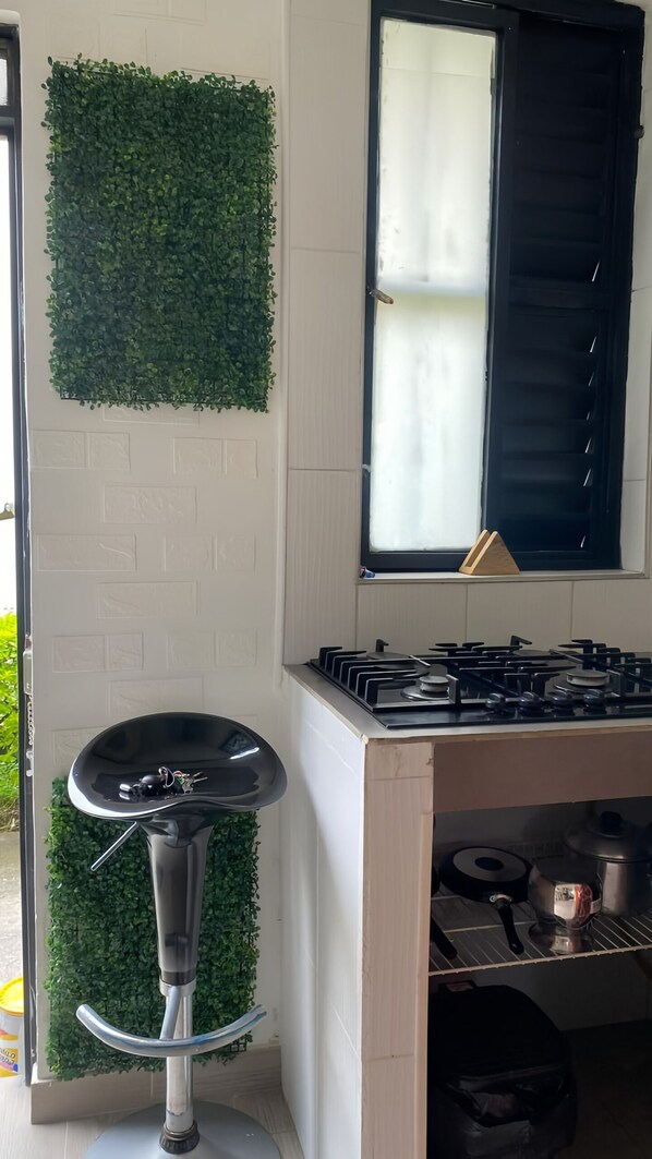 A kitchen with a gas stove, a sink, and a window with a curtain.