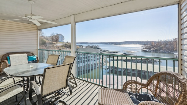Un balcon avec une table et des chaises, donnant sur une étendue d’eau et une côte lointaine.
