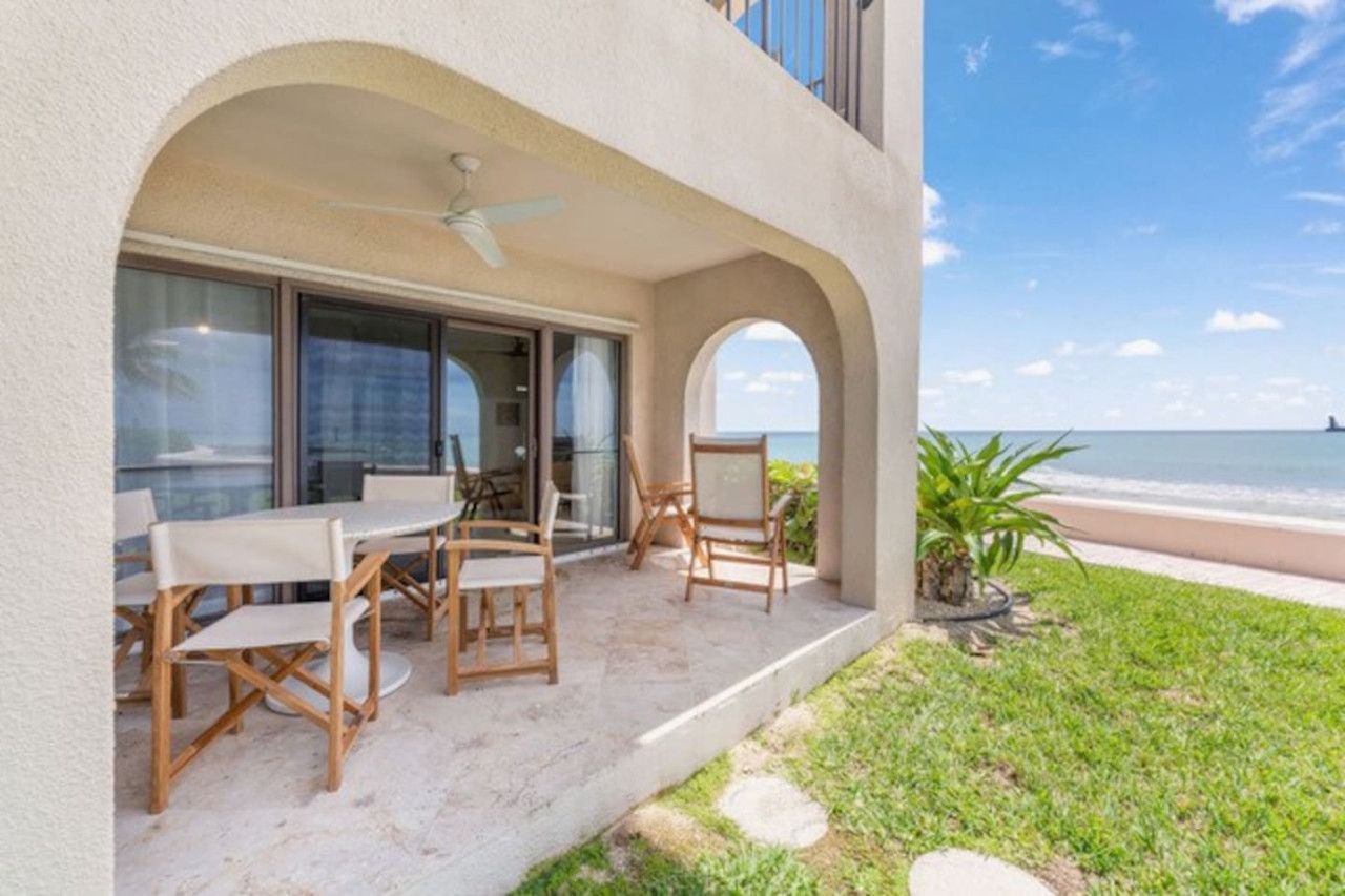 Un área de estar al aire libre y techada con vista al mar.