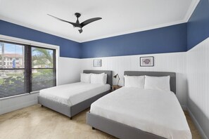 A bedroom with two beds, a ceiling fan, and a window with blinds. - Oceanfront, Pool & Patio | Family/Couples Paradise (George Town)